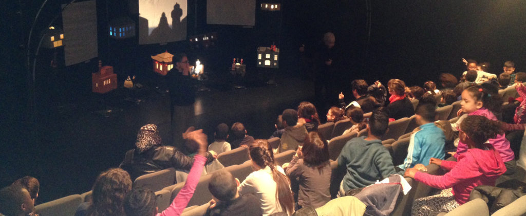 An auditorium with schoolchildren sat watching the stage.